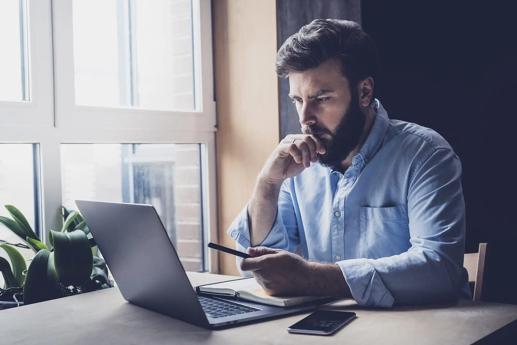 Man holding phone, looking at computer, Healthtech Resources, Inc., Healthcare IT, Phoenix, AZ.